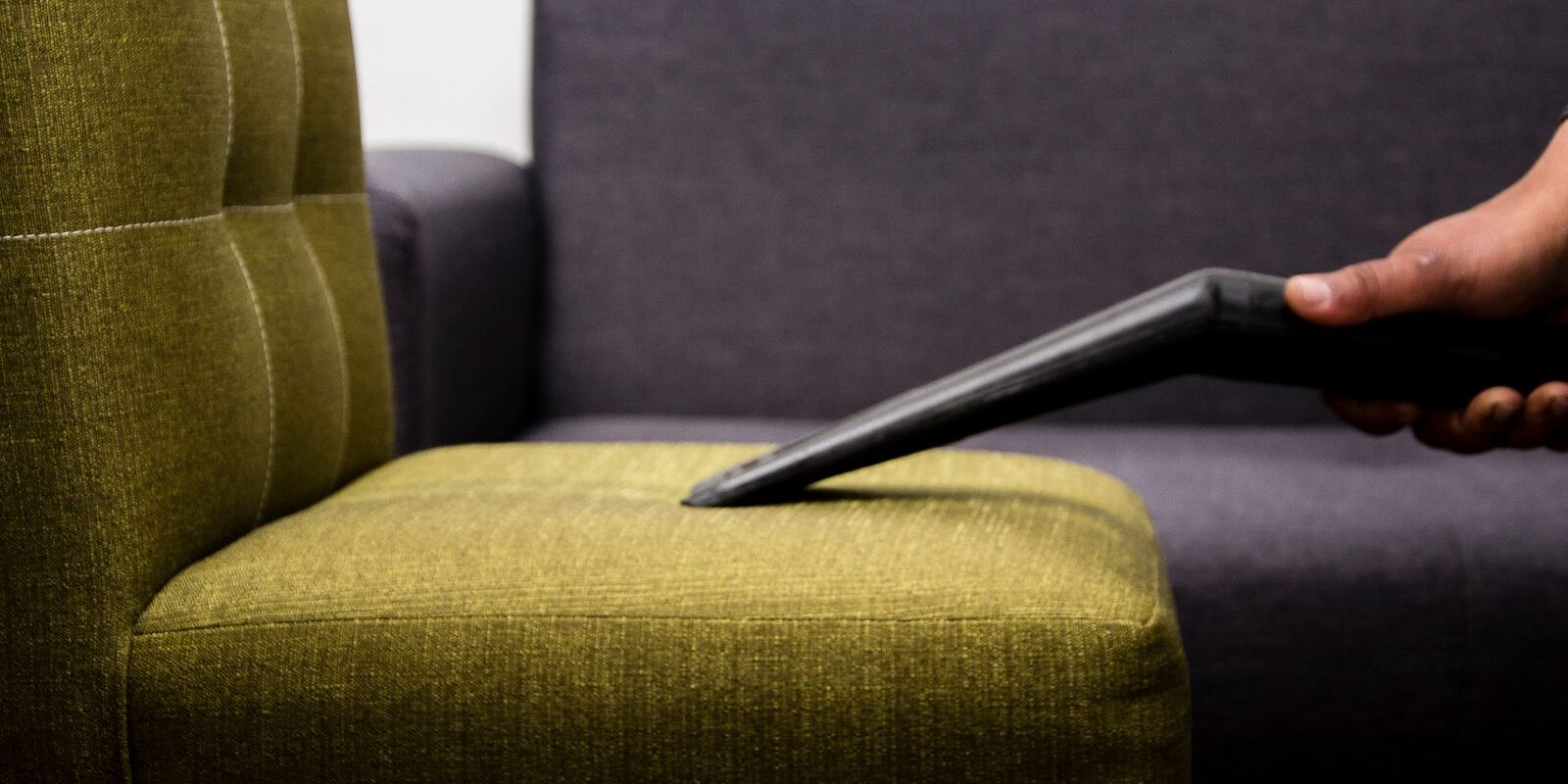 Stoffen fauteuil wordt van dichtbij gestofzuigd met een meubelmondstuk om kruimels en stof te verwijderen