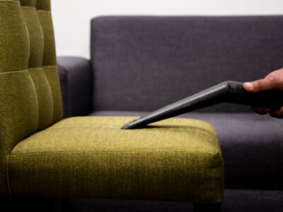 Stoffen fauteuil wordt van dichtbij gestofzuigd met een meubelmondstuk om kruimels en stof te verwijderen
